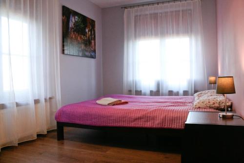 sypialnia z łóżkiem z różową pościelą i oknami w obiekcie Apartament Sandomierskie Wzgórze w mieście Sandomierz