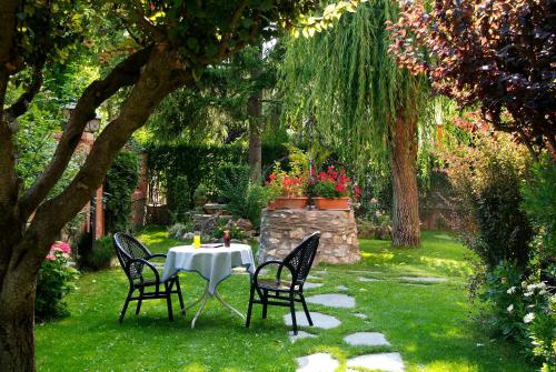 una mesa y sillas en un jardín bajo un árbol en Aero Hotel Cerdanya Ca L'eudald, en Alp