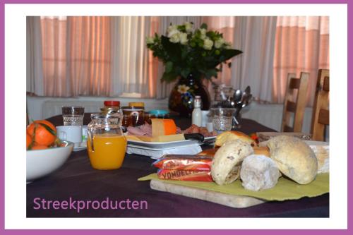 una mesa con pan y zumo de naranja y un plato de comida en Guesthouse Kolibriehuys, en Nieuwkerke