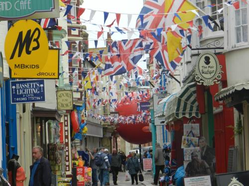 a street with lots of flags and people walking down it at Driftwood B&B Weymouth in Weymouth