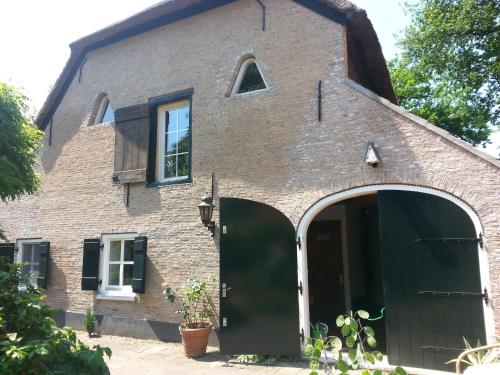 an old brick house with a large green door at B & B De Pimpelmees in 's-Gravenmoer