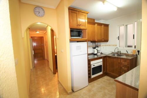 トレビエハにあるDaniela apartamentの白い冷蔵庫付きのキッチン、壁掛け時計