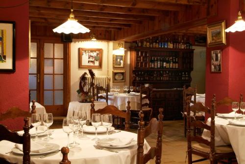Aero Hotel Cerdanya Ca L'eudald في ألب: غرفة طعام مع طاولات بيضاء وكراسي مع أكواب