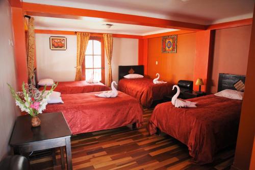 Una habitación de hotel con tres camas con cisnes. en Tunupa Lodge Hotel, en Ollantaytambo
