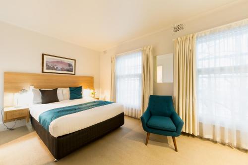 a bedroom with a bed and a blue chair at Customs House Hotel in Hobart