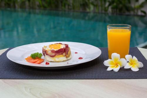 een bord met ontbijtproducten en een glas sinaasappelsap bij The Rinaya Canggu by ecommerceloka in Canggu