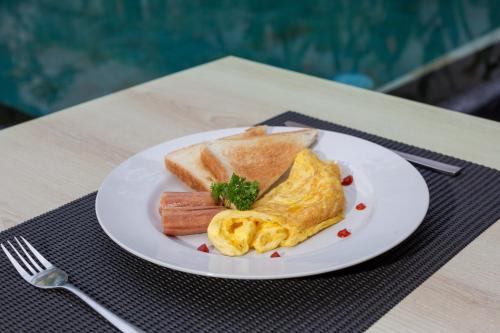 een bord ontbijtproducten met eieren, worst en toast bij The Rinaya Canggu by ecommerceloka in Canggu