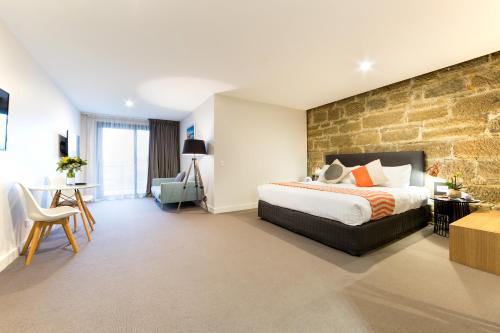 a hotel room with a bed and a brick wall at Customs House Hotel in Hobart