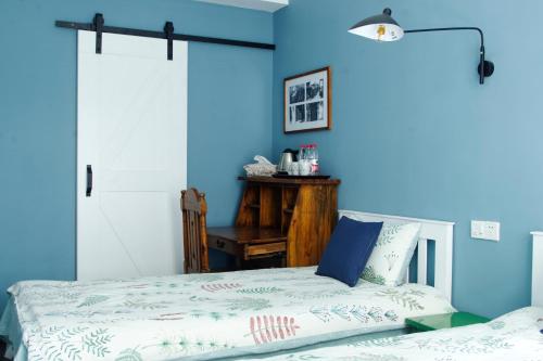 a bedroom with a bed and a blue wall at Hangzhou JiuYueJi Bed&Breakfast in Hangzhou