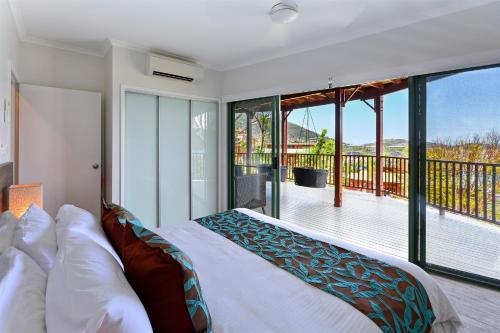 a bedroom with a bed and a balcony at Casuarina Cove Apartments in Hamilton Island