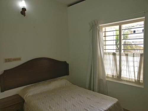 a bedroom with a bed and a window at Safire Residency in Trivandrum