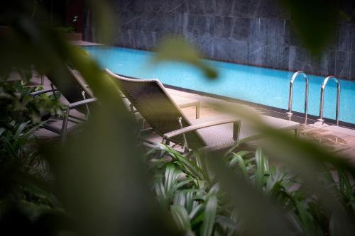 two chairs sitting next to a swimming pool at Hotel Mi Bencoolen in Singapore