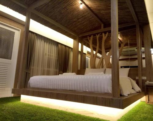 - une chambre avec un grand lit et des draps blancs dans l'établissement Nava Grand, à Ban Talat Rangsit