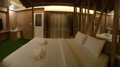 a bedroom with a large white bed with towels on it at Nava Grand in Ban Talat Rangsit