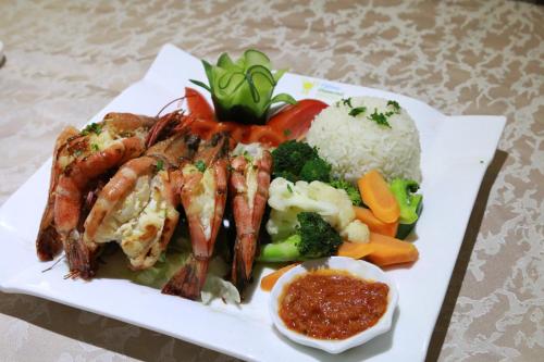 a plate of food with shrimp and rice and vegetables at Tiffany Diamond Hotels Ltd - Indira Gandhi street in Dar es Salaam