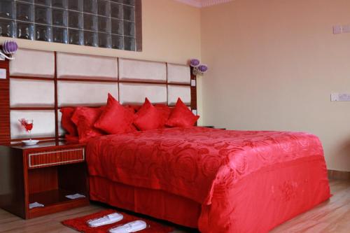 a red bed with red pillows in a bedroom at Tiffany Diamond Hotels Ltd - Indira Gandhi street in Dar es Salaam