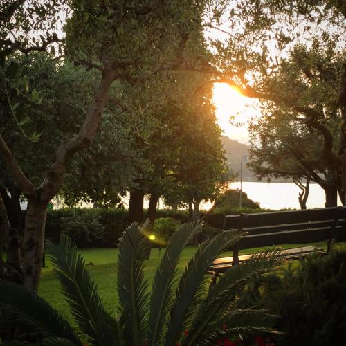 a bench in a park with the sunset in the background at Villa Kinzica in Sale Marasino