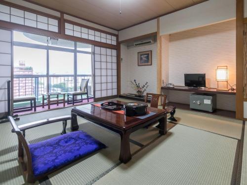a living room with a table and a balcony at Riverside Hotel Shoei in Kochi