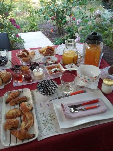 - une table avec petit-déjeuner composé de viennoiseries et de jus d'orange dans l'établissement Au Jardin de Lisa, à Cherreau