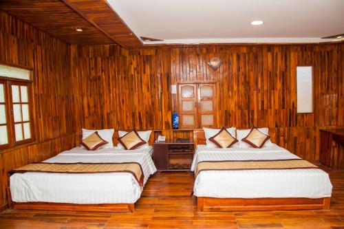 two beds in a room with wooden walls at Satraco Royal Hotel in Soc Trang