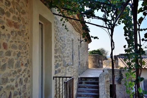 a stone building with stairs and a tree next to it at Chambres d'hôtes au Mas du Sire in Quissac