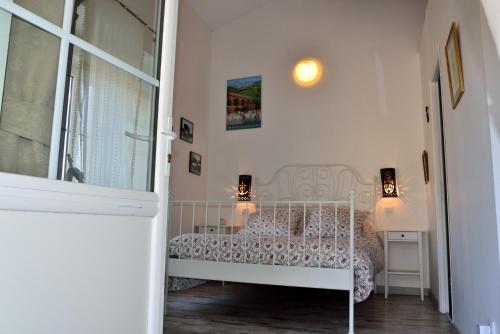 a white bedroom with a bed and a window at Chambres d'hôtes au Mas du Sire in Quissac