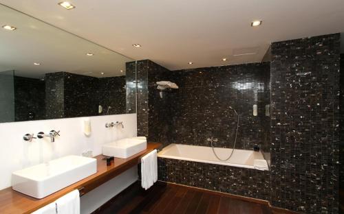 a bathroom with two sinks and a bath tub at Hotel Zhero in Cas Catala