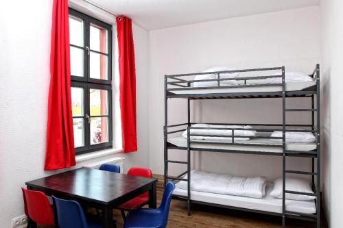 ノイブランデンブルクにあるHostel am GÜTERBAHNHOFのテーブルと二段ベッドが備わる客室です。