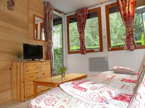 um quarto com uma cama, uma televisão e janelas em 2 Pièces+Terrasse CHAMONIX CENTRE em Chamonix-Mont-Blanc