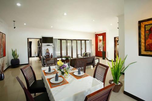 a dining room and living room with a table and chairs at Villa L'Orange Bali in Keramas