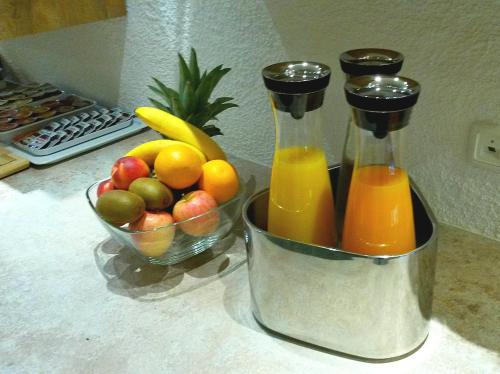 two bottles of orange juice and a bowl of fruit at Hotel Alp Inn - Chiemgaukarte inclusive in Ruhpolding