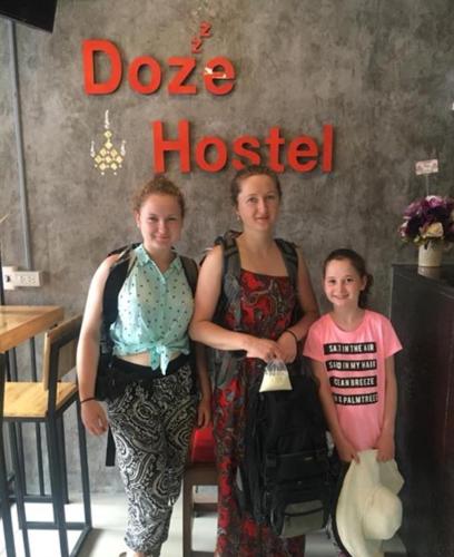 a group of three women standing in front of a dog house at Doze Hostel in Chiang Mai