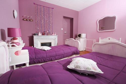 Un dormitorio morado con dos camas y chimenea. en La Renardière, en Saint-Sauveur-de-Montagut