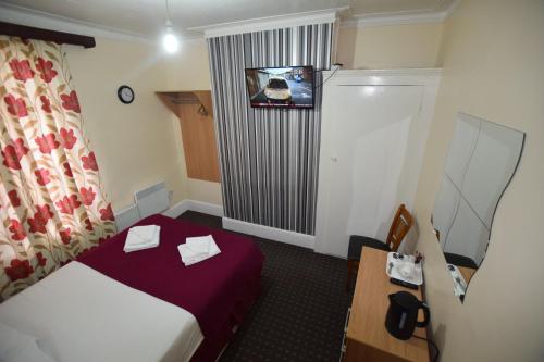 a hotel room with a bed and a tv on the wall at Woodlands Lodge Ilford in Ilford