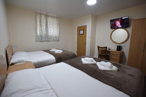 a hotel room with two beds and a mirror at Woodlands Lodge Ilford in Ilford