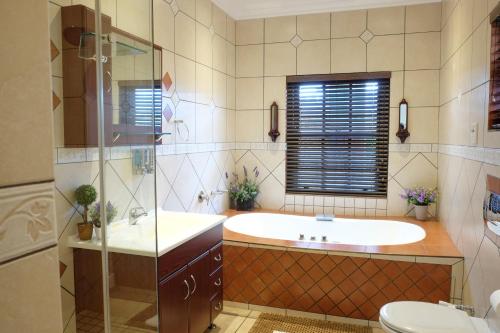 un bagno con vasca, lavandino e WC di Waterkloof Guest House a Pretoria