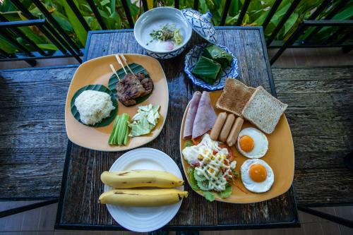 two plates of breakfast food on a wooden table at Himaphan Boutique Resort - SHA EXTRA PLUS in Nai Yang Beach