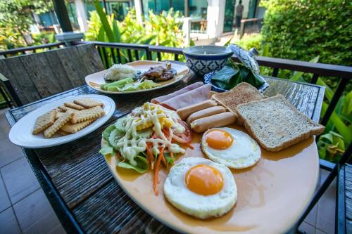 a table with two plates of breakfast food on it at Himaphan Boutique Resort - SHA EXTRA PLUS in Nai Yang Beach
