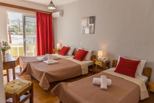 a hotel room with two beds with red pillows at Tsambika Sun Hotel in Archangelos