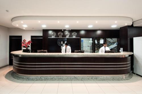 two men standing at a bar in a restaurant at Serras Hotel in Cuiabá