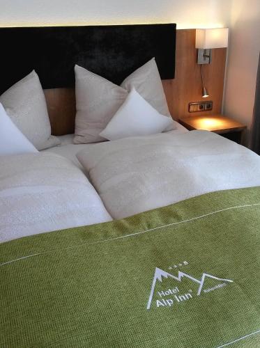 a large white bed with a green blanket on it at Hotel Alp Inn - Chiemgaukarte inclusive in Ruhpolding