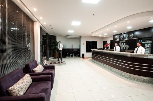 a lobby with a bar with two men standing at a counter at Serras Hotel in Cuiabá