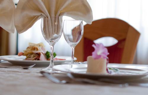 a table with two wine glasses and a plate of food at Hotel Al Cervo in Tesero