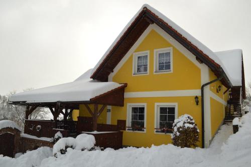 a yellow house with snow on top of it at Chalupa Dana in Víchová nad Jizerou
