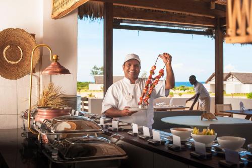 a chef holding up a bunch of food in a kitchen at Mequfi Beach Resort in Mecúfi