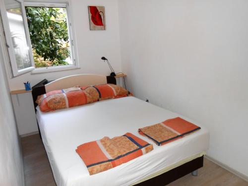 a bedroom with a white bed with a window at Gogi apartman in Okrug Donji