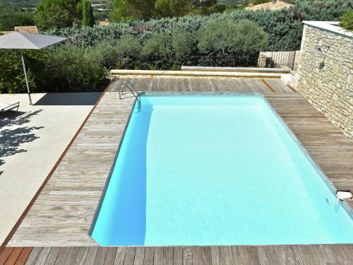 une piscine dans une cour arrière avec une terrasse en bois et une piscine bleue dans l'établissement Villa in Roussillon with Private Pool, à Roussillon