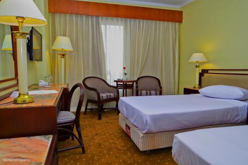 a hotel room with two beds and a table and chairs at Resta Port Said Hotel in Port Said