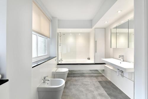 a white bathroom with two toilets and a sink at Chiltern Street Serviced Apartments - Marylebone in London