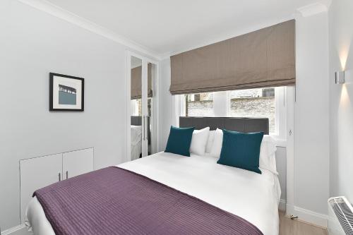 a bedroom with a large bed with blue pillows at Chiltern Street Serviced Apartments - Marylebone in London